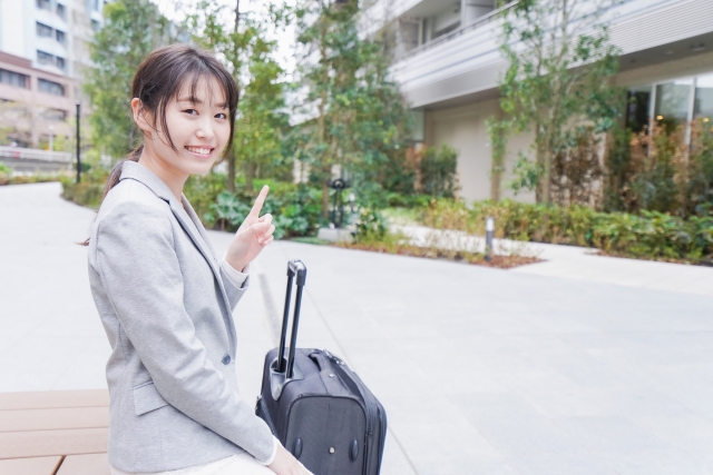 スーツケースと指さす女性